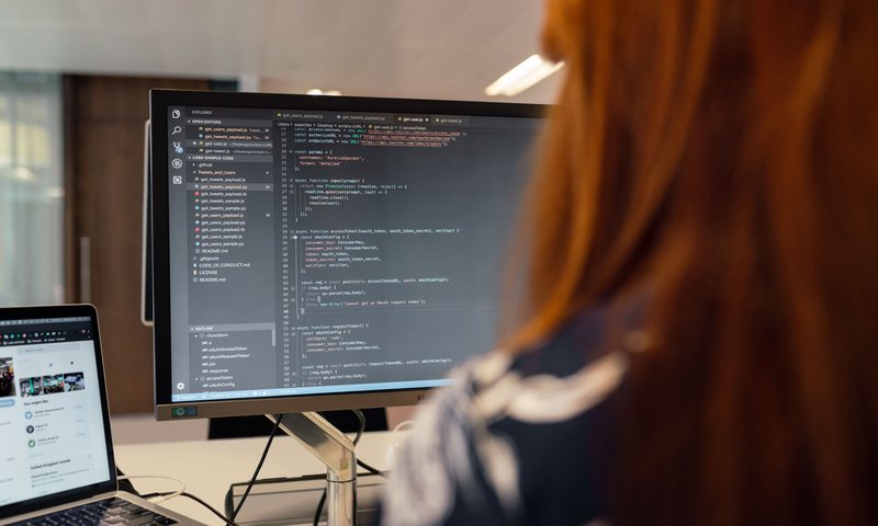 Software engineer coding on a large monitor