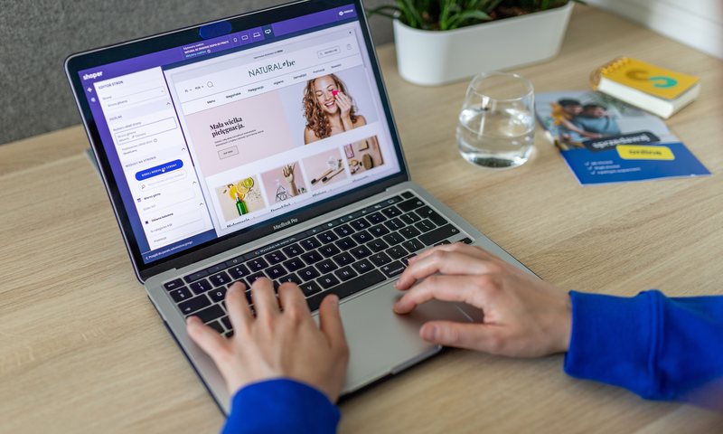 Hands typing on a laptop displaying an e-commerce website
