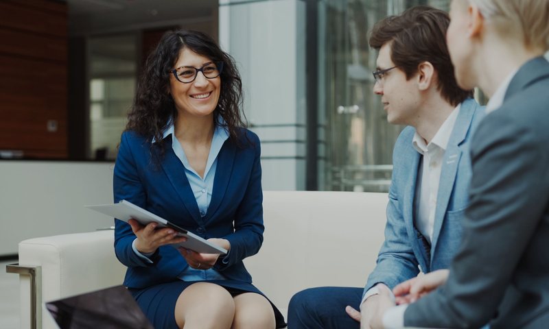 Consultant in navy blazer collaborating with clients over a tablet