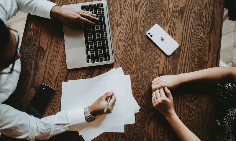 Overhead view of two professionals working together with laptop and notes